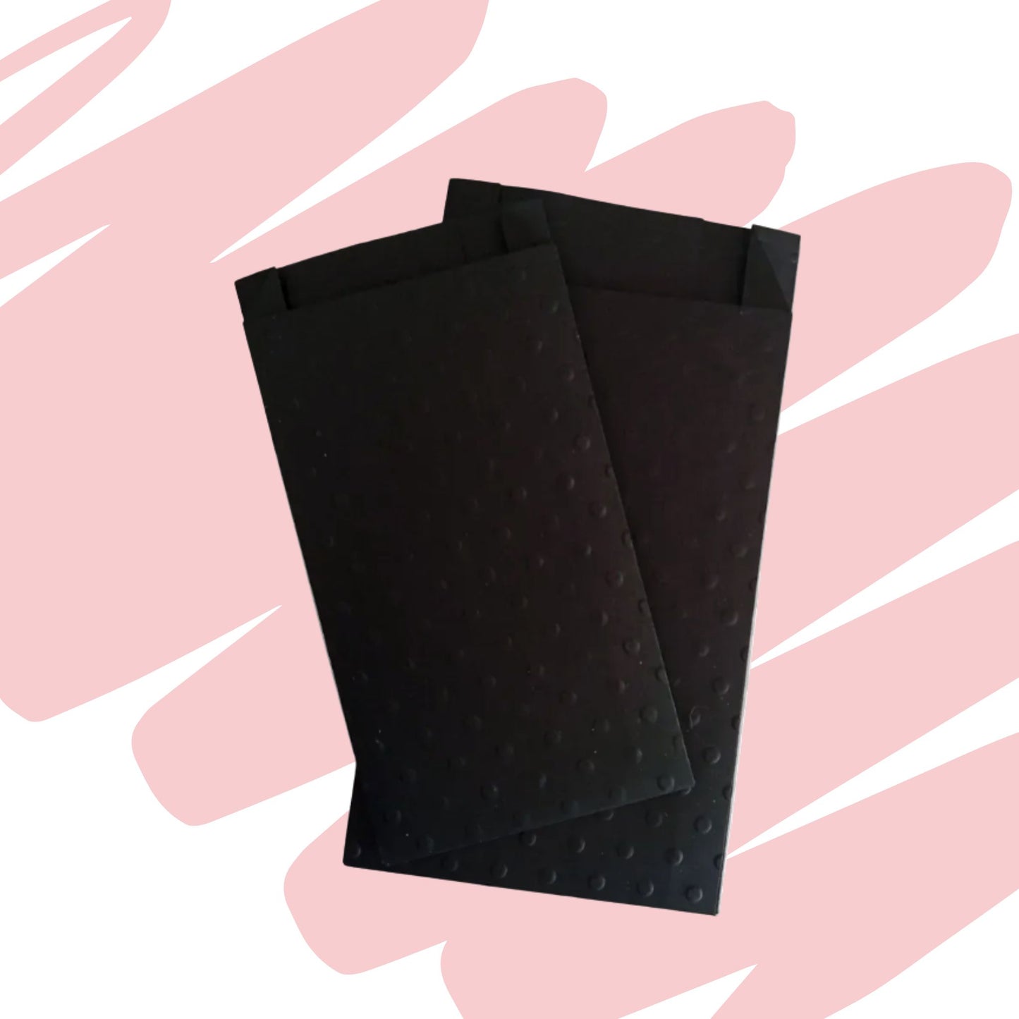 Due sacchetti neri con texture goffrata a piccoli rilievi, leggermente sovrapposti l'uno all'altro su uno sfondo decorato con pennellate rosa chiaro e bianche.