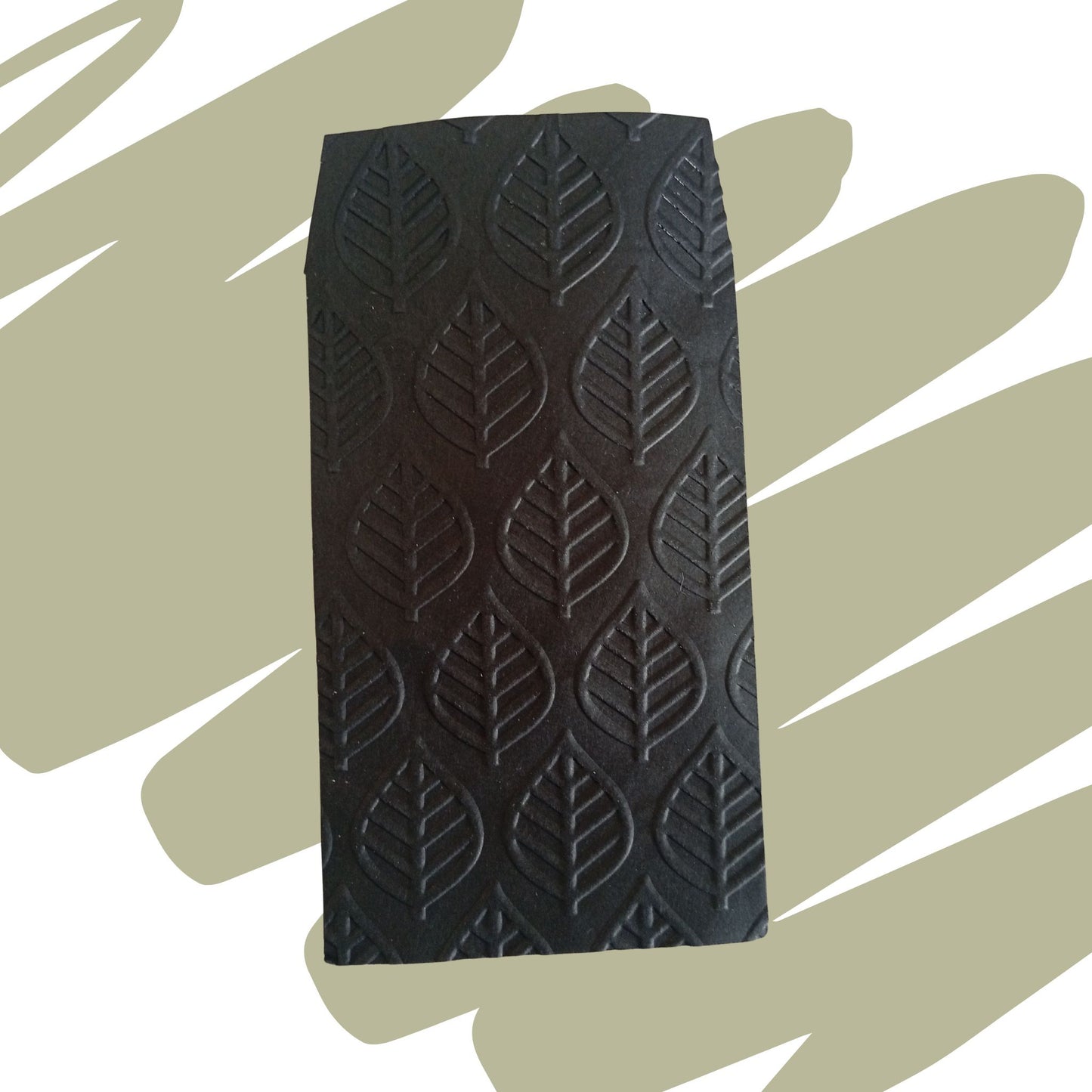 Inquadratura ravvicinata e verticale di un sacchetto nero caratterizzato da una texture in rilievo con un motivo decorativo a foglie ramificate, disposto su uno sfondo verde oliva e bianco.