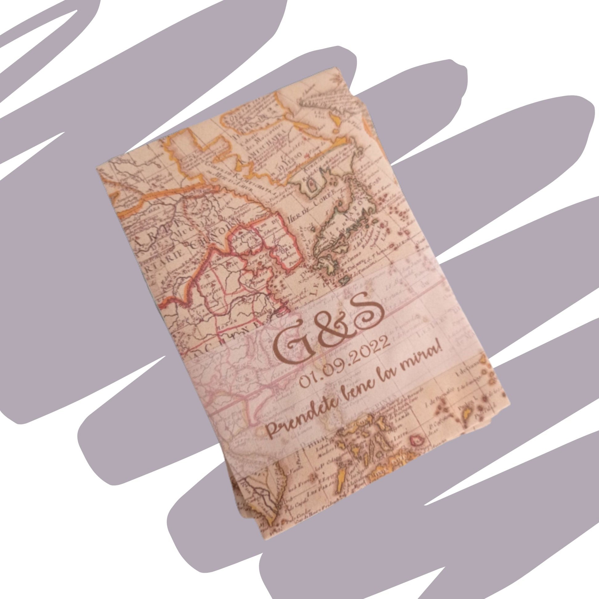 Sacchetto portaconfetti o bustina regalo in carta stampata con la grafica di una mappa geografica antica in stile vintage. Personalizzato con le iniziali "G&S", la data "01.09.2022" e la frase ironica "Prendete bene la mira!" stampate in color marrone seppia, posizionato su uno sfondo grigio con pennellate.