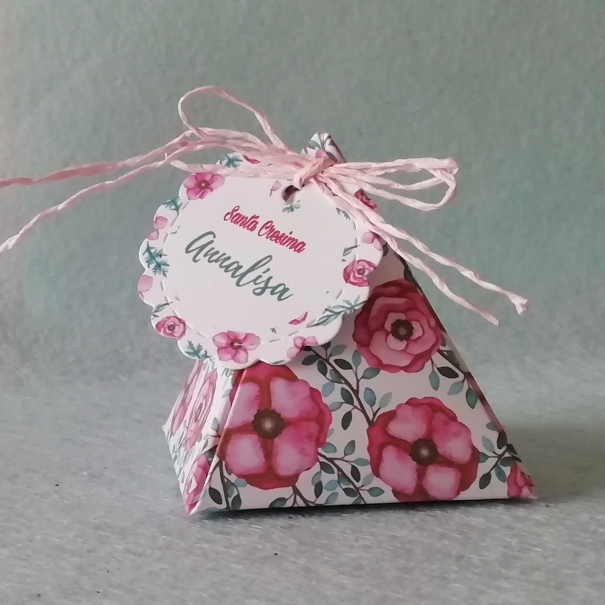un portaconfetti a forma di piramide con una fantasia floreale moderna sui toni del verde smeraldo e rosa con tag abbinato con scitto santa cresima e il nome della cresimanda