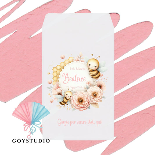sacchetto portaconfetti bianco per battesimo/nascita bimba su sfondo rosa. Design con ape kawaii e alveare, circondati da una ghirlanda botanica rustica rosa e beige. In basso, nome personalizzato "Beatrice" e scritta "Grazie per essere stati qui"