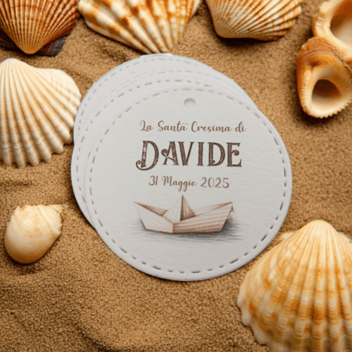 Bigliettini rotondi carta tema mare cresima personalizzati con barchetta di carta e conchiglie su sabbia
